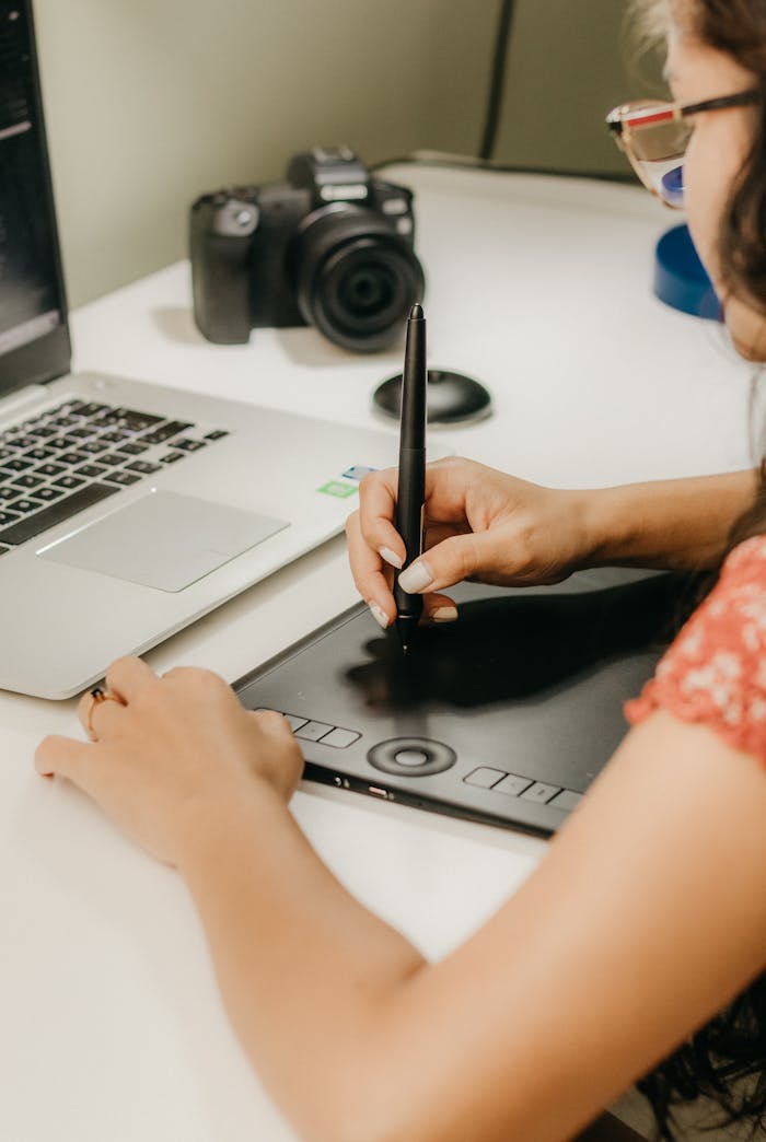 Young woman working with graphic tablet and laptop in a creative workspace.